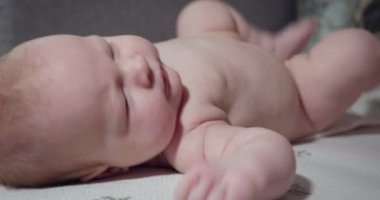 Küçük bebek yatakta yatar ve arkasını döner..