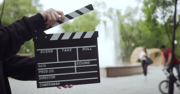 Unrecognizable man claps with clapperboard outdoors. — Stock Video