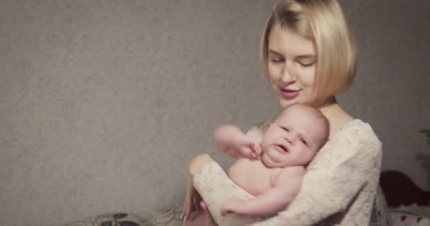 A fiatal anya tartja és nyugtatja a kislányát.. — Stock videók