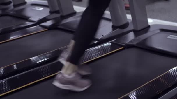 Vue sur les baskets de femme sportive courant sur le tapis roulant au gymnase — Video