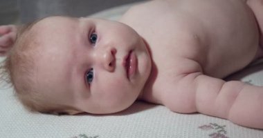 Küçük bebek yatakta yatar ve arkasını döner..