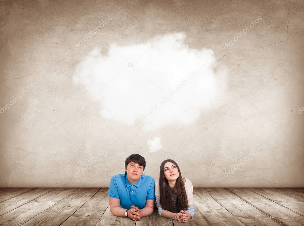 Young couple lying on the floor in apartment and dreaming.