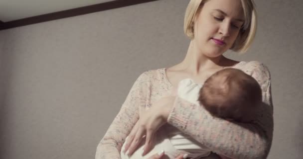 Jonge moeder brengt haar kleine baby in slaap. — Stockvideo
