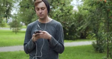 Hippi, yaz parkında akıllı telefondan müzik dinliyor..