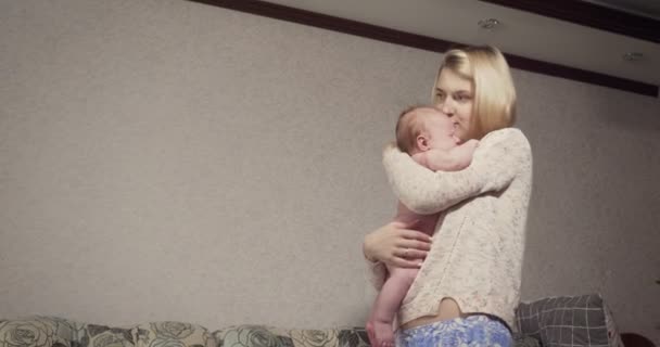 Молода мати тримає і заспокоює свою маленьку дівчинку . — стокове відео