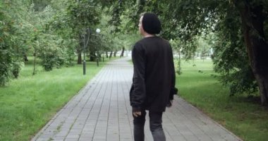 Arkadaki adam açık havada teypten müzik dinliyor.