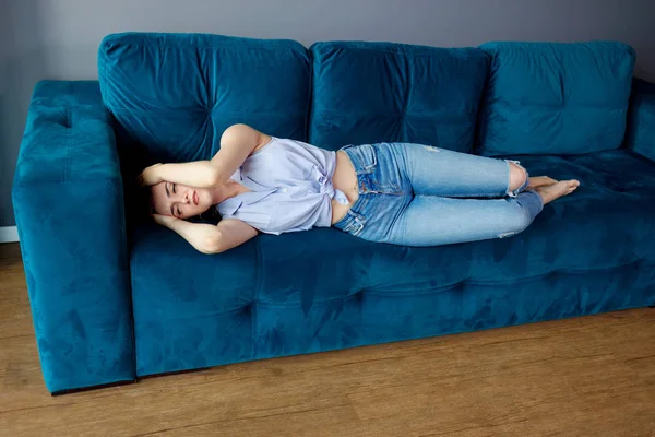 Jonge vrouw liggend op de bank en lijden aan hoofdpijn. — Stockfoto