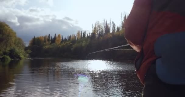 Vista trasera del pescador lanza un caño de pescar en el río . — Vídeo de stock