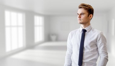 Beyaz ofis arka planında poz veren bir iş adamı.