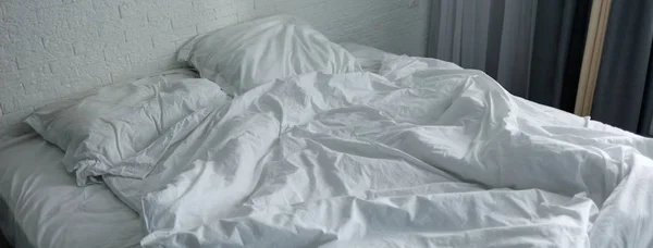Desarrumado cama amassada com roupas de cama brancas . — Fotografia de Stock