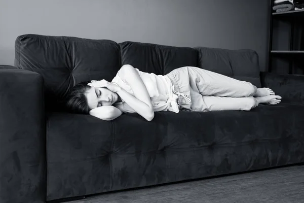 Młoda kobieta leży na kanapie i cierpi na ból głowy w domu. — Zdjęcie stockowe