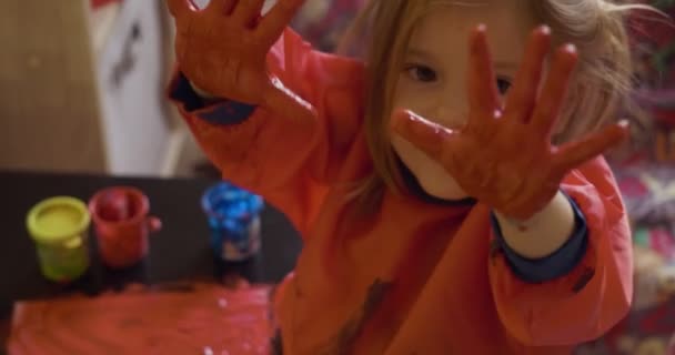 Joyeux petite fille avec les mains en dessin de peinture rouge — Video