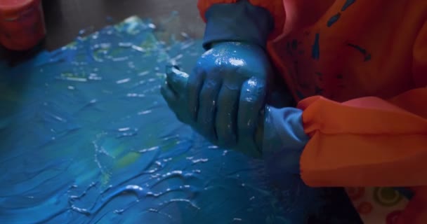 Gelukkig klein meisje met handen in blauw verf tekening — Stockvideo
