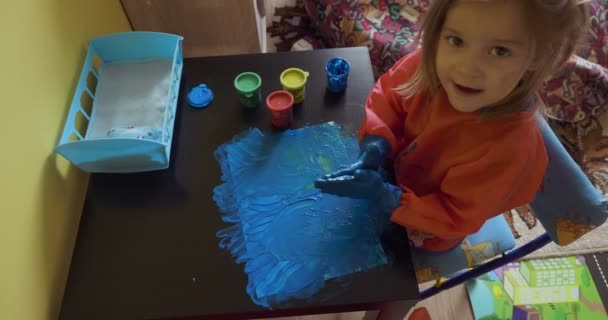 Menina feliz com as mãos no desenho de pintura azul — Vídeo de Stock