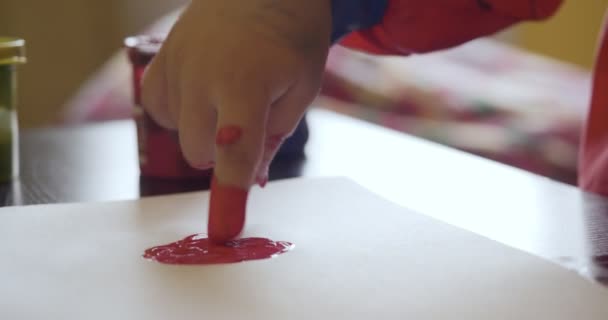 Gelukkig klein meisje met handen in rood verf tekening — Stockvideo