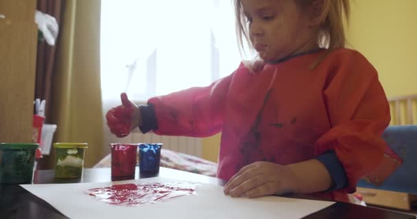 Niña feliz con las manos en el dibujo de pintura roja — Vídeo de stock