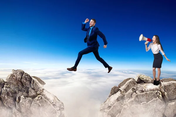 Бизнесмен прыгает со скалы, а босс аплодирует мегафону. . — стоковое фото