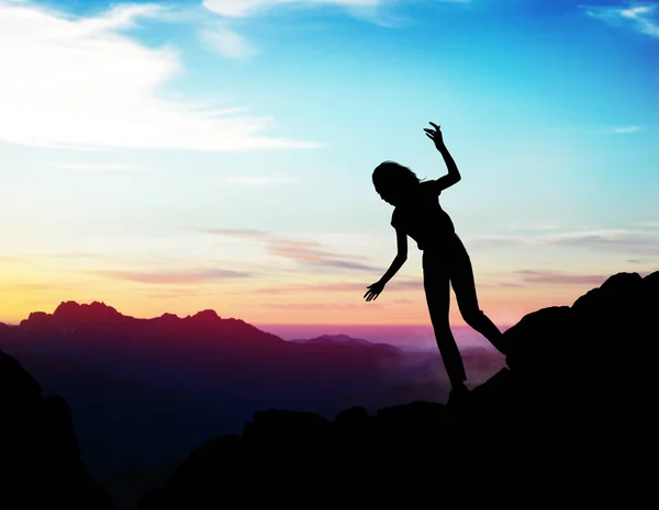 Black silhouette of woman walking down of rock. — Stock Photo, Image