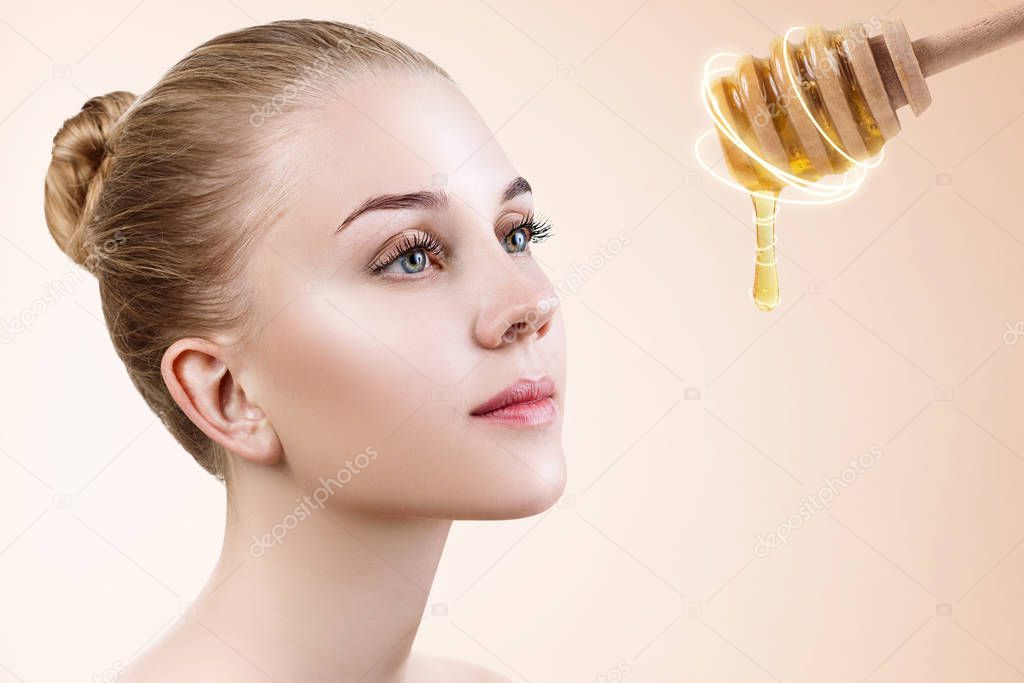 Young woman and honey spoon prepare for facial mask.