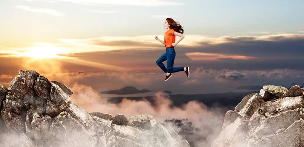 Ginger woman jumping through the gap among mountains. — Stock Photo, Image