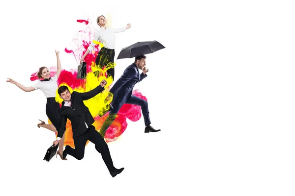 Happy office workers jumping in suits among colorful inks exlosion. — Stockfoto
