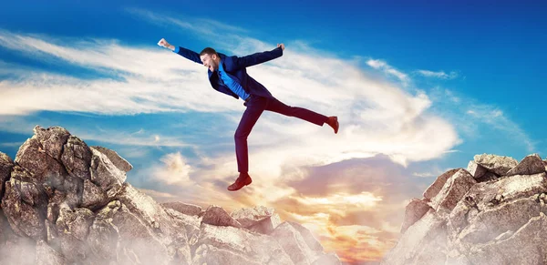 Young businessman flying through the gap among mountains. — Stock Photo, Image
