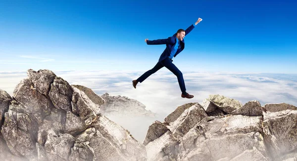 Young businessman flying through the gap among mountains. — Stock Photo, Image