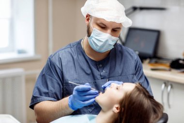 Genç kadın hastaya dişçi muayenesi.