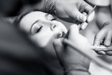 Dişçi klinikteki genç kadın hastaları tedavi ediyor..