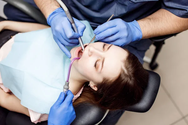歯医者はクリニックで若い女性患者に歯を治療する. — ストック写真