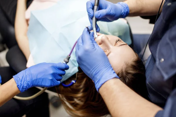 Dentiste traitant les dents à une jeune patiente en clinique . — Photo