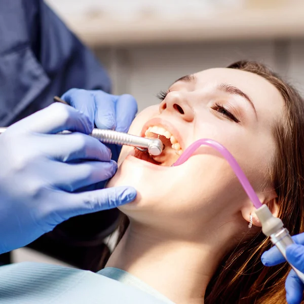 Dentiste traitant les dents à une jeune patiente en clinique . — Photo