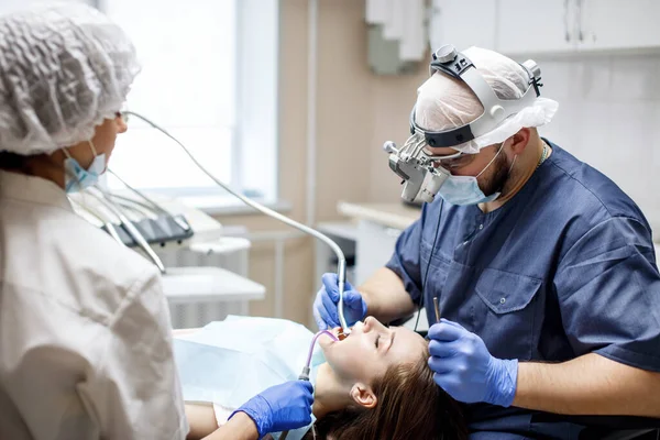 진료소에서 젊은 여성 환자에게 치아를 치료하는 치과 의사. — 스톡 사진
