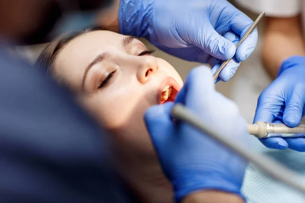 Dentista che cura i denti a una giovane paziente in clinica . — Foto Stock