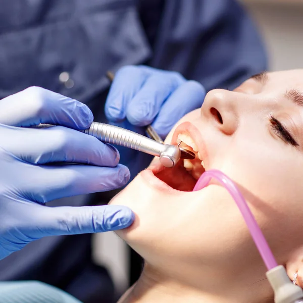 Tandläkare som behandlar tänder till ung kvinna patient på kliniken. — Stockfoto