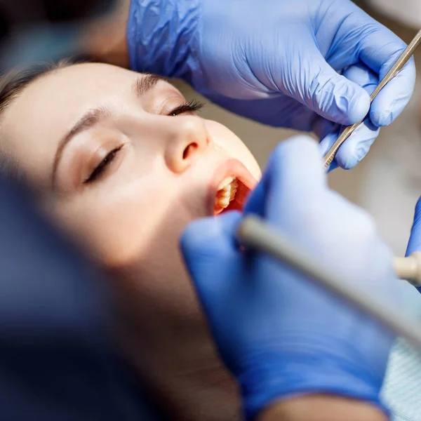 Dentista che cura i denti a una giovane paziente in clinica . — Foto Stock