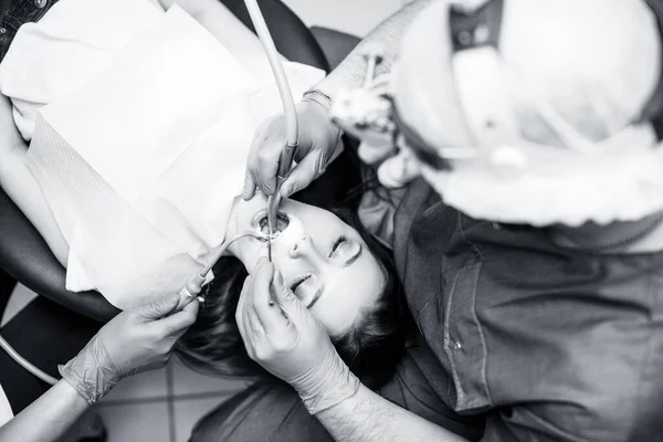 Dentiste traitant les dents à une jeune patiente en clinique . — Photo