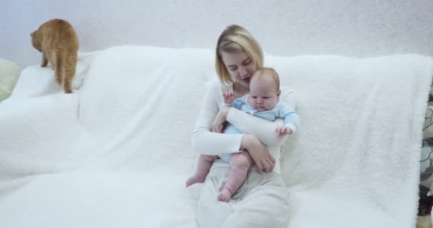 Madre sostiene a su bebé sentado en el sofá . — Vídeos de Stock