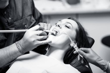 Dişçi klinikteki genç kadın hastaları tedavi ediyor..