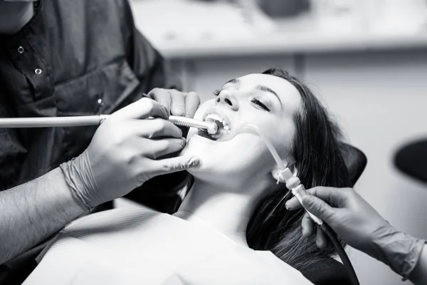 Dentist treating teeth to young woman patient in clinic. — Stock Photo, Image