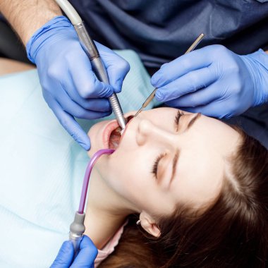 Dişçi klinikteki genç kadın hastaları tedavi ediyor..