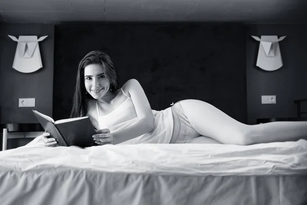 Rudowłosa kobieta leży i relaksuje się na łóżku i zagląda do pamiętnika. — Zdjęcie stockowe