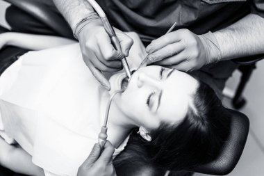 Dişçi klinikteki genç kadın hastaları tedavi ediyor..