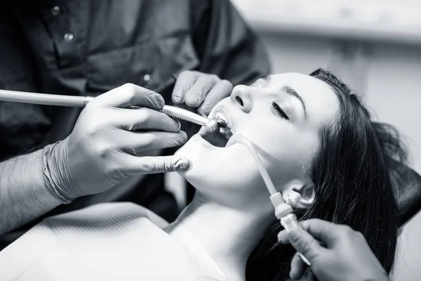 歯医者はクリニックで若い女性患者に歯を治療する. — ストック写真