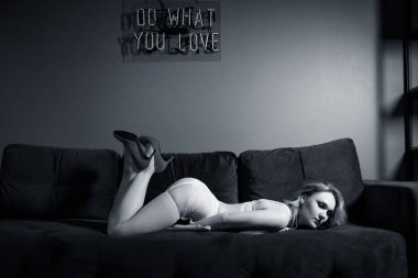 Beyaz iç çamaşırlı seksi kadın mavi koltukta pembe seks oyuncağı tutuyor..