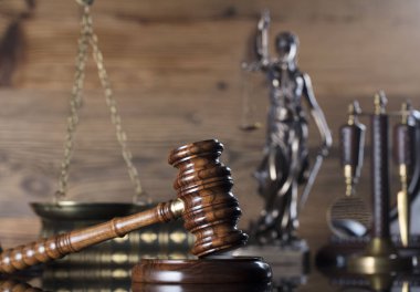 Adalet, ölçek, tokmak ve ahşap arka plan üzerinde kitap heykeli.