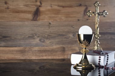 Katolik dini Tema. Çapraz, Holy Bible ve ahşap zemin üzerine altın kadeh.