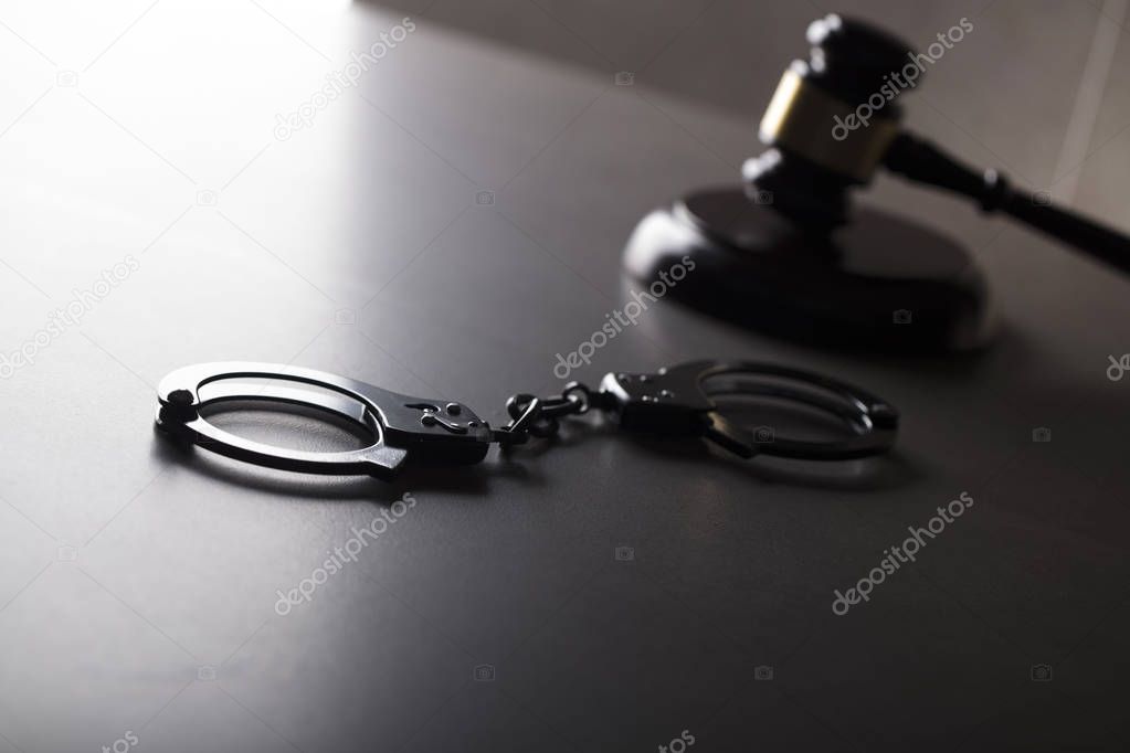 Criminal law concept. Cuffs and jugde gavel on stone background.