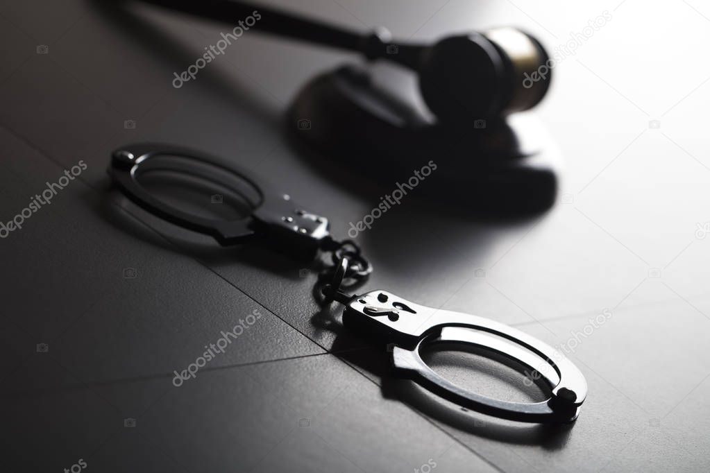 Criminal law concept. Cuffs and jugde gavel on stone background.