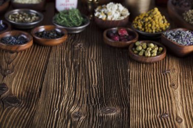 Doğal Tıp arka plan. Pirinç harç, şişe ve ölçek. Rustik tablo. Çeşitli kuru otlar kase. Bokeh.